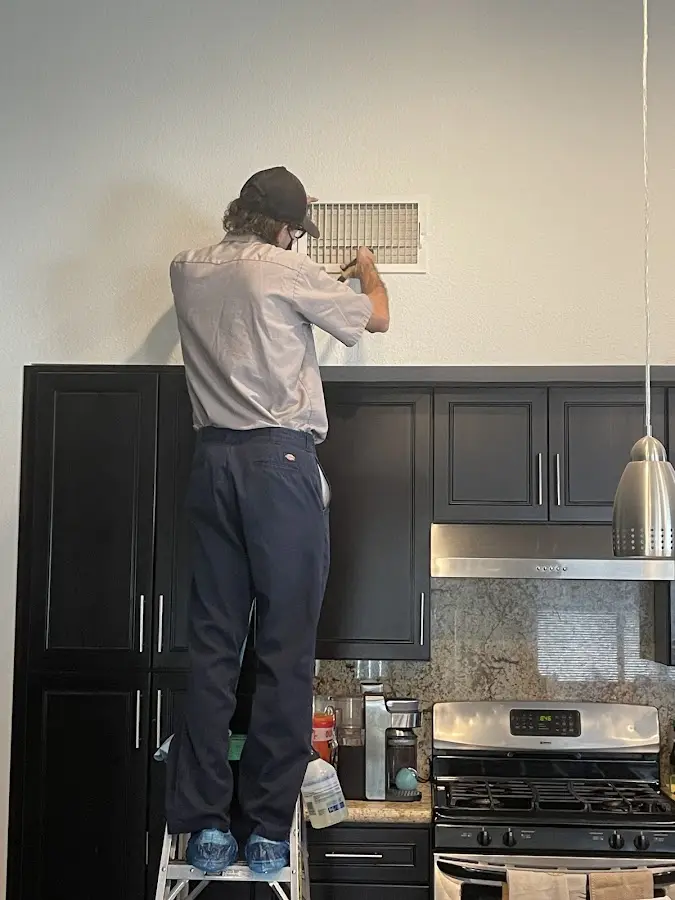 Technician inspecting an air vent during HVAC service in Blytheville